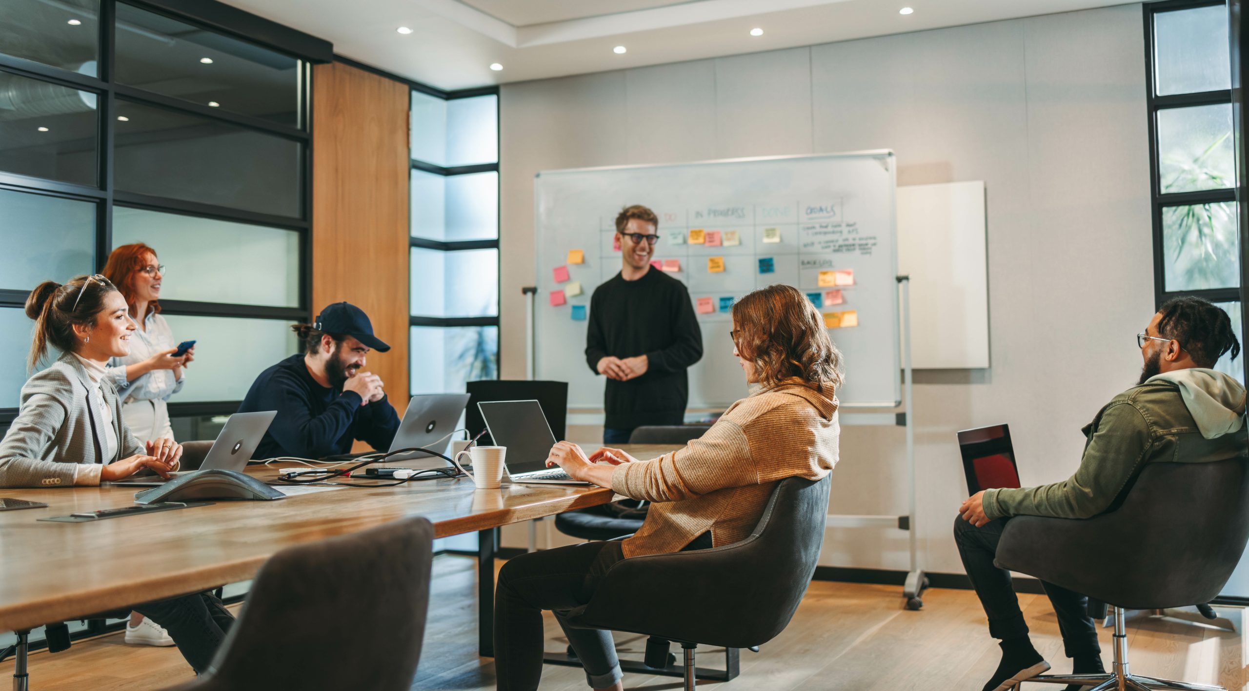 Dans une salle de réunion moderne, plusieurs dirigeants et entrepreneurs échangent avec un consultant autour d’un tableau rempli de notes colorées. Ordinateurs ouverts, discussions dynamiques, ambiance collaborative : chacun apporte son expertise pour structurer une réponse à un appel d’offres. Cette scène illustre l’accompagnement proposé par le Groupe Novances, qui aide les entreprises de toutes tailles à analyser les cahiers des charges, optimiser leurs propositions et remporter de nouveaux marchés grâce à une approche stratégique, rigoureuse et humaine.
