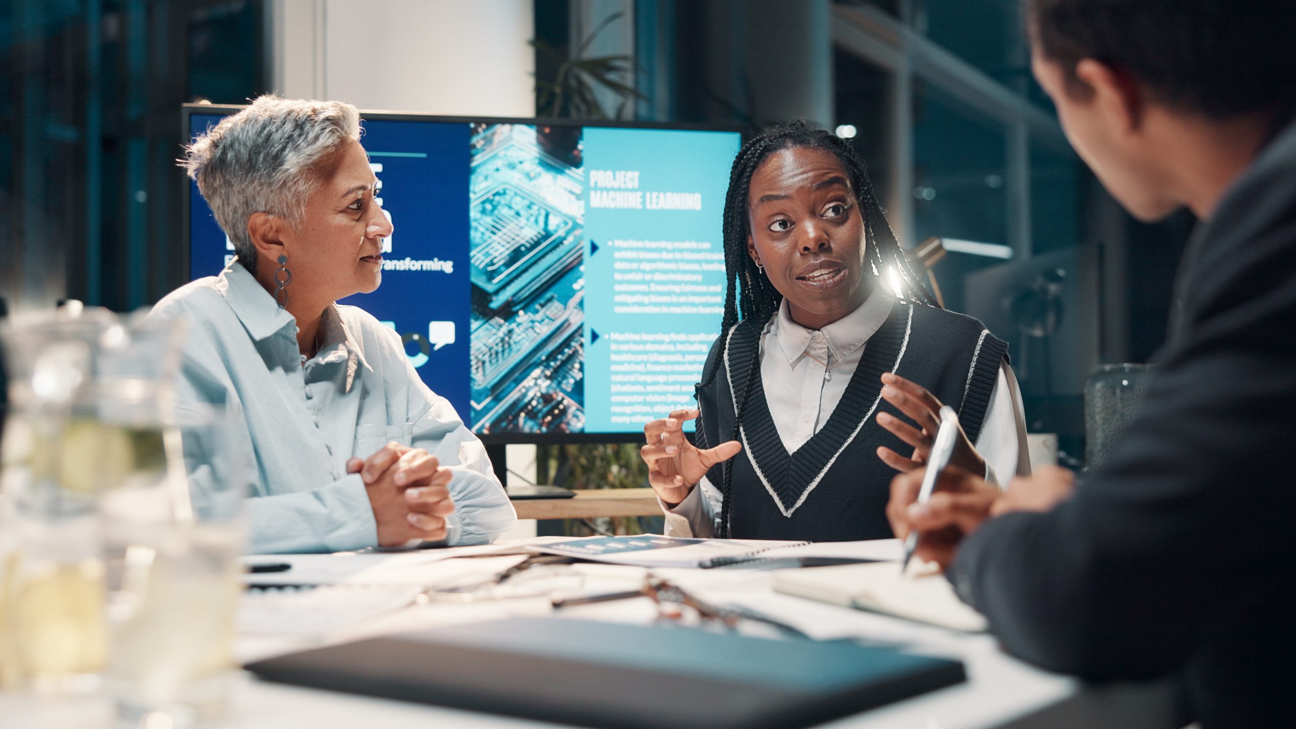 Dans une salle de réunion moderne, des experts du Groupe Novances échangent avec des dirigeants autour d’un projet d’intégration logicielle. Sur l’écran en fond, des données et schémas techniques illustrent la mise en place de nouveaux outils connectés. Cette scène reflète l’accompagnement proposé par Novances : connecter, harmoniser et optimiser les logiciels pour simplifier la gestion, fiabiliser le pilotage et fluidifier l’organisation au quotidien.