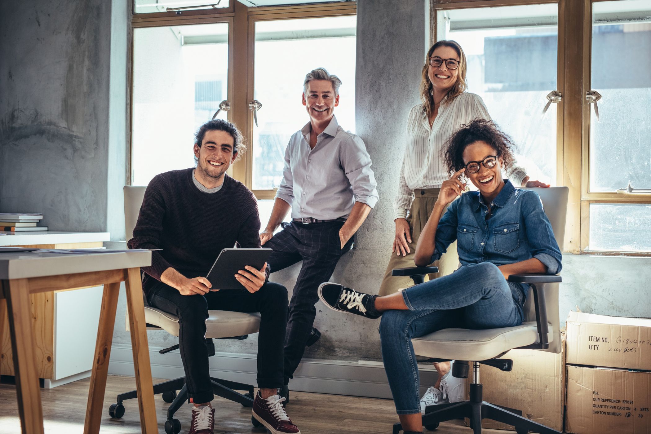 Équipe souriante dans un nouveau bureau en cours d’installation, illustrant l’ouverture de nouveaux sites et la proximité renforcée du groupe Novances avec ses clients.